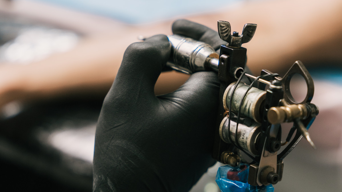 un tatoueur tient son matériel de professionnel entre ses mains